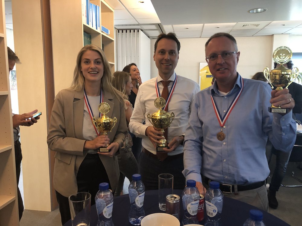 Winning team holding trophies and medals at the Boskamp Willems office